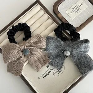 Chouchous nœuds en tricot et peluche avec pompons dans un coffret en bois