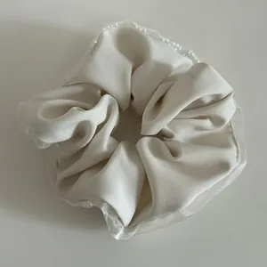 Detail of cream scrunchie with pearl edge trim and delicate lace mesh fabric