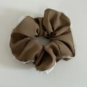Detail of coffee brown scrunchie with white lace edges and small pearl beads