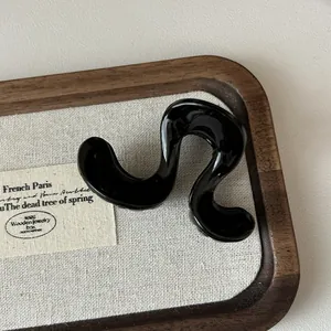 Glänzende schwarze gewellte Haarklammer auf rustikalem Tablett für elegante Frisuren