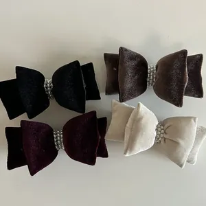 Detail von vier Samt-Haarschleifen in Schwarz, Braun und Beige mit Perlenverzierung