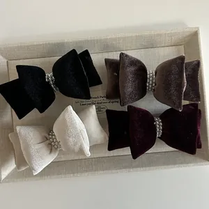 Elegante Samt-Haarschleifen mit Perlen in vier Farben auf einem strukturierten Tablett
