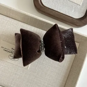 Details von dunkelbrauner Samt-Bogen-Haarspange mit Silberperlen in einer Geschenkbox