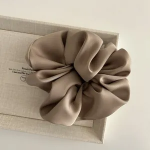 Macro detail of a large mocha satin scrunchie showing smooth silk texture and soft folds