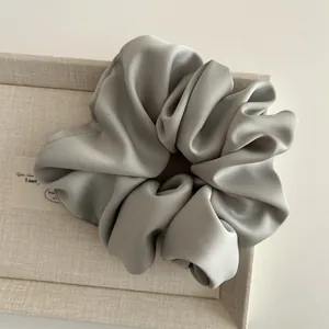 Macro shot of large matte satin scrunchie in misty blue with rich fabric texture and folds