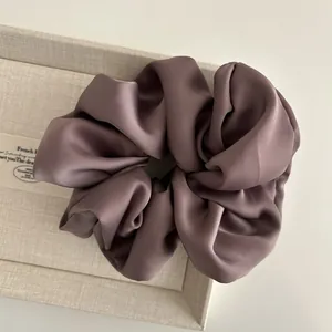 Close-up of silk satin scrunchie in mauve color with elegant folds and soft texture