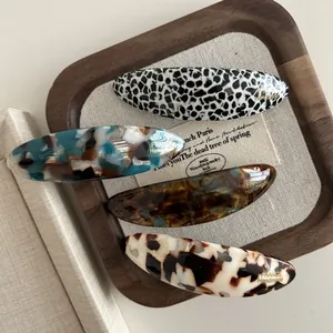 Set of four French-style oval acetate hair clips in assorted marble and tortoiseshell patterns