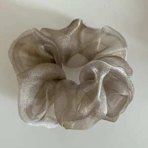 Macro detail of champagne organza scrunchie with shimmering translucent texture and soft pleats