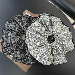 Close-up of oversized chiffon floral scrunchies in black and white contrasting patterns