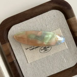 Macro detail of marbled acetate hair clip with golden Flower Handmade text on fabric