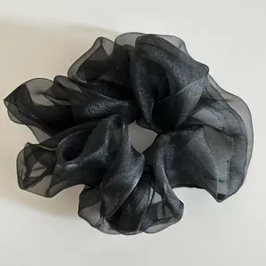 Macro shot of large black organza scrunchie with layered pleats and translucent texture