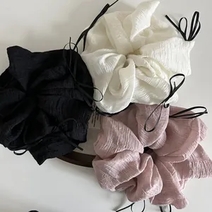 Three oversized seersucker scrunchies in black, white, and pink with long black ribbons