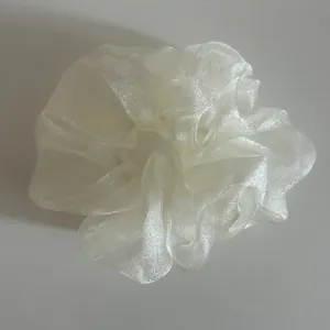 Detailed close-up of ivory pearlescent organza scrunchie with soft ruffled texture
