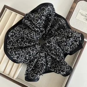 Detail of oversized floral scrunchie featuring vintage black and white print and satin edging