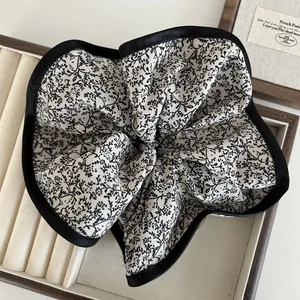 Detail of oversized floral scrunchie with black satin piping edge in a wooden display box