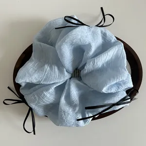 Detail of light blue textured scrunchie featuring three black ribbon bow accents
