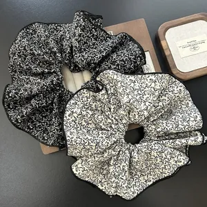 Macro detail of oversized floral chiffon scrunchies with elegant wavy contrast edging