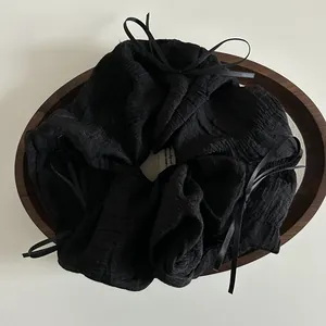 Detail of black pleated fabric scrunchie with ribbon bows on a wooden tray
