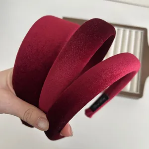Three burgundy velvet headbands with handmade tags showing various widths and styles