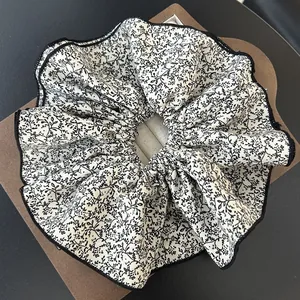 Detailed macro view of large chiffon scrunchie with floral print and black stitched edges