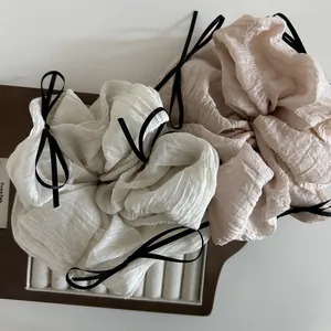 Detail of cream and beige oversized scrunchies with black silk ribbon bow accents
