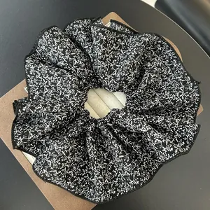 Detail of large black scrunchie with white floral print on brown cardboard display
