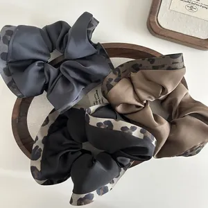 Vintage leopard print satin scrunchies in charcoal, brown, and black displayed in a wooden tray