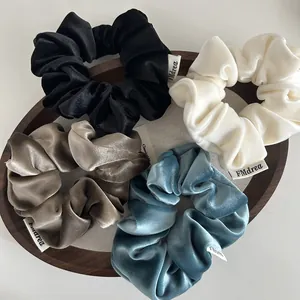Velvet hair scrunchies in four classic colors presented on a luxury wooden tray