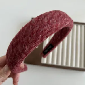 Macro di un cerchietto in peluche rosso scuro con trama morbida e spessa imbottitura