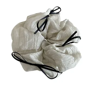 Oversized white scrunchie with black ribbon bows made of pleated chiffon fabric