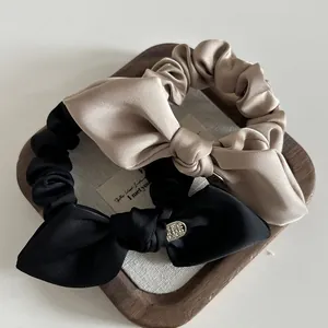 Set of satin bow hair scrunchies in champagne and black with elegant metal tags