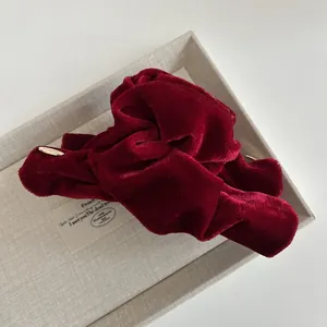 Close-up of velvet hair claw clip in burgundy with elegant gold metal logo tag