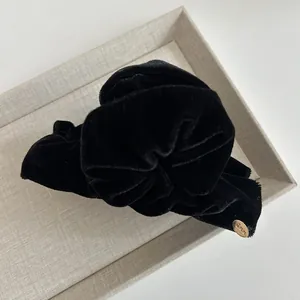 Macro detail of high-quality black velvet hair tie with a branded gold metal charm