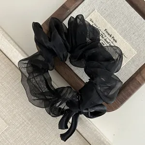 Detail of black mesh scrunchie with bowknot on vintage wooden background textures