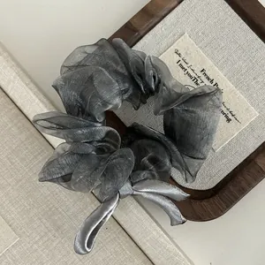 Detailed texture of gray organza hair scrunchie with satin bow on wooden tray
