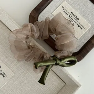 Detail of champagne organza scrunchie with olive green satin bow in vintage French style