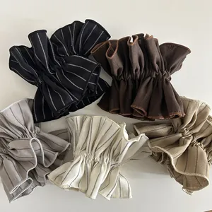 Detail view of five assorted striped and solid fabric scrunchies with pleated edges