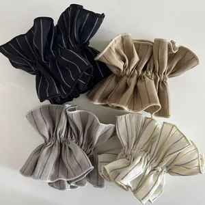 Detailed view of striped scrunchies in black, beige, grey, and white cotton fabric