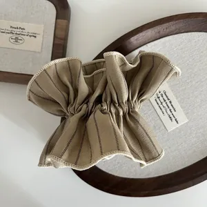 Detailed shot of a khaki striped scrunchie with pleated texture on a wooden tray