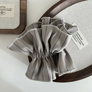Close-up of gray striped scrunchie with detailed stitching and soft cotton linen texture