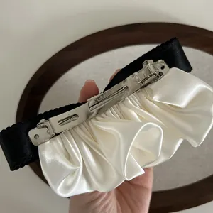 Détail de la pince à ressort argentée et du ruban de satin crème sur la barrette à nœud