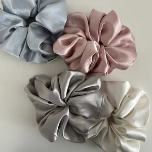 Set of four glossy satin scrunchies in light blue, pink, silver, and beige colors