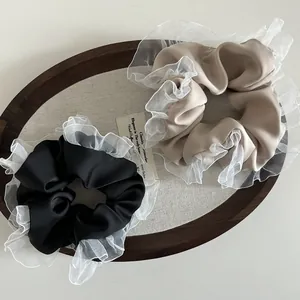 Macro detail of French vintage satin scrunchies with elegant double-layered lace edges
