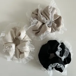 Close-up of pleated chiffon scrunchies with white lace edges in beige, khaki, and black