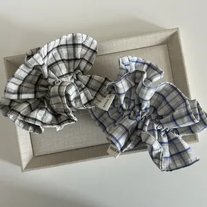 Elegant checkered ruffle scrunchies set in blue and black plaid fabric on a tray