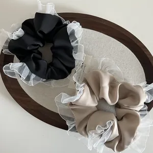 Detail of vintage ruffled organza scrunchies in black and khaki on a wooden tray