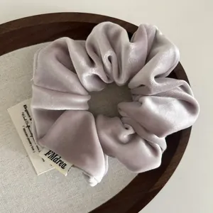 Elegant light purple velvet scrunchie displayed on a minimalist wooden jewelry tray