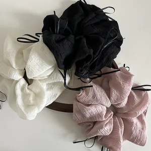 Close-up of oversized pleated chiffon scrunchies in black, white, and pink with ribbons