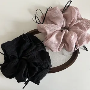 Macro view of oversized pleated chiffon scrunchies in black and pink with ribbon bow