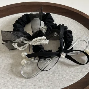 Dettaglio macro di elastici per capelli in organza nera con perle eleganti e fiocchi decorativi